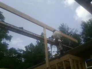 Carpenter setting a ridge beam over a new addition frame — Ice Dam Removal by Roofing Brothers in Breezy Point