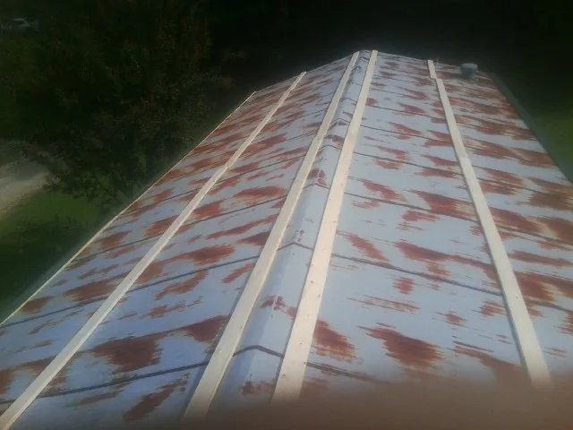 Rusted metal roof panels with new wood purlins before replacement — Storm Damage Roof Repair in Breezy Point by Roofing Brothers