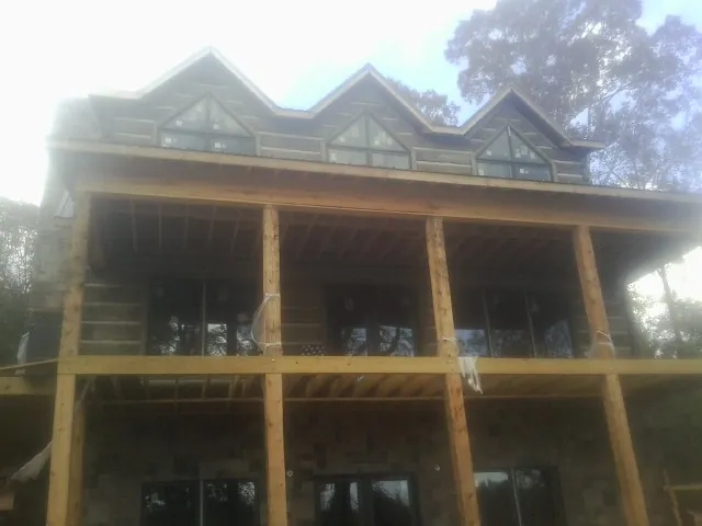 Dormers and porch framing on a large log home under construction — Roof Coating work by our crew in Breezy Point
