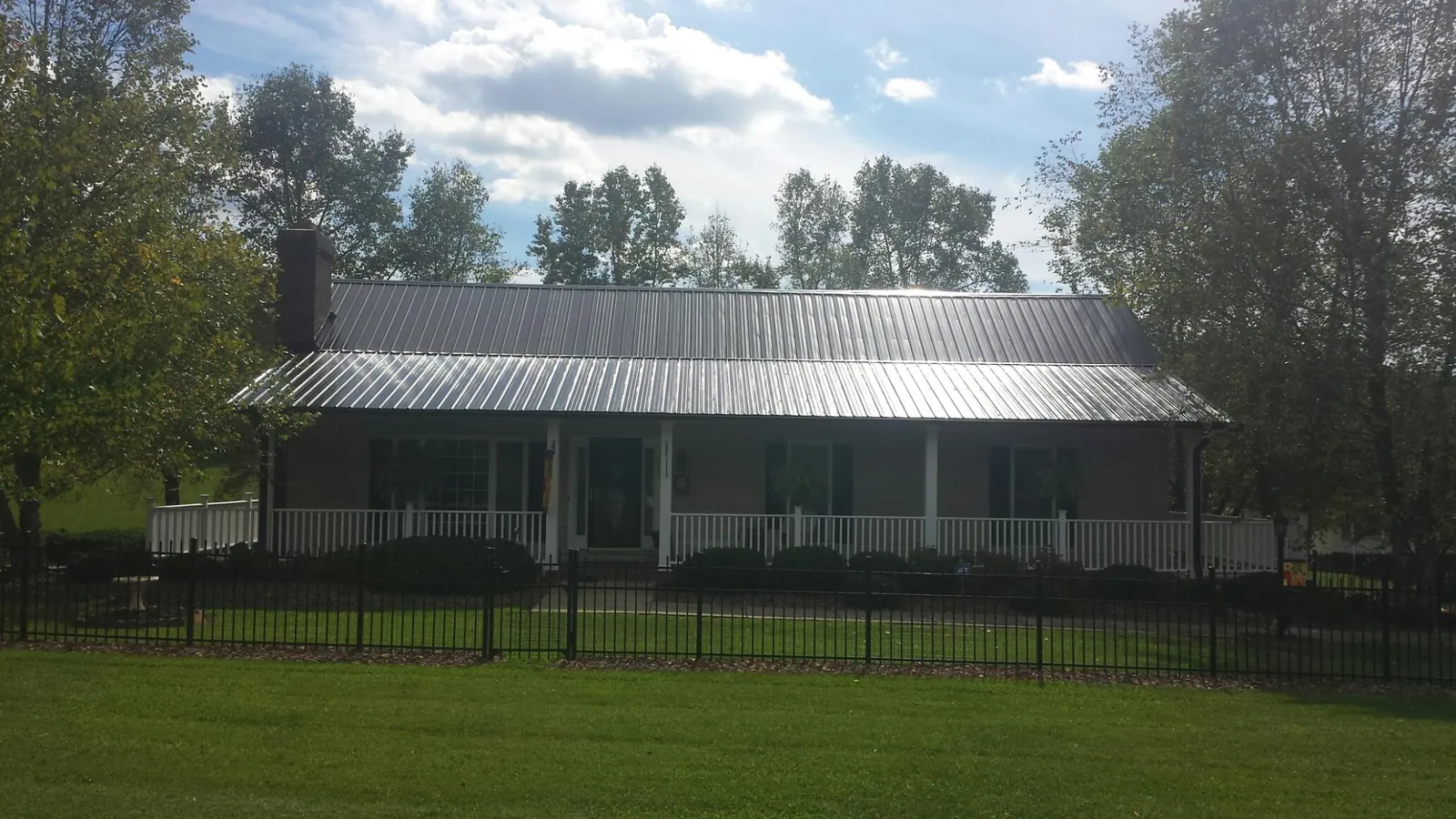 Gray metal roof on a brick ranch with a full width front porch — Gutter Guard Installation work by our crew in Breezy Point