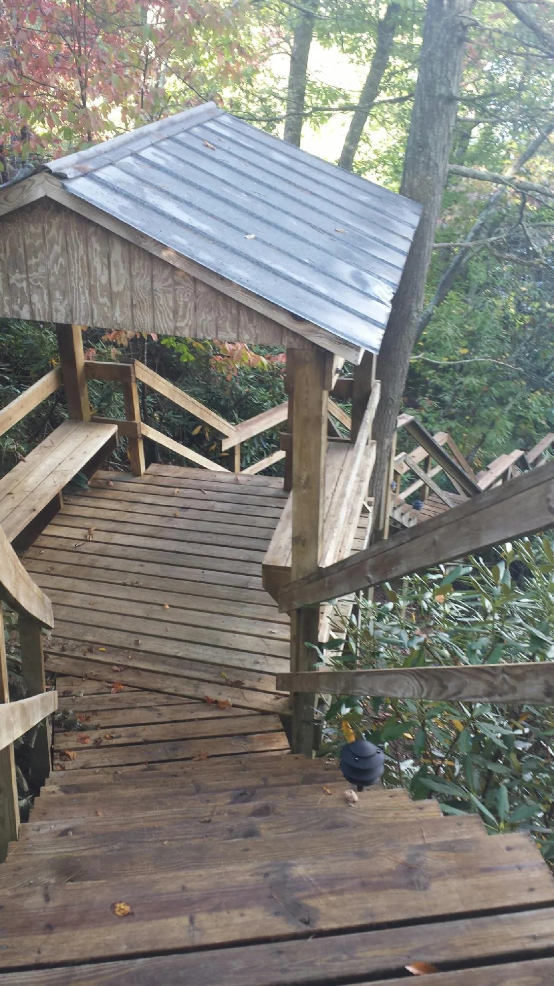 Metal roofed shelter over wooden steps on a wooded walkway — Skylight Repair & Installation work by our crew in Breezy Point